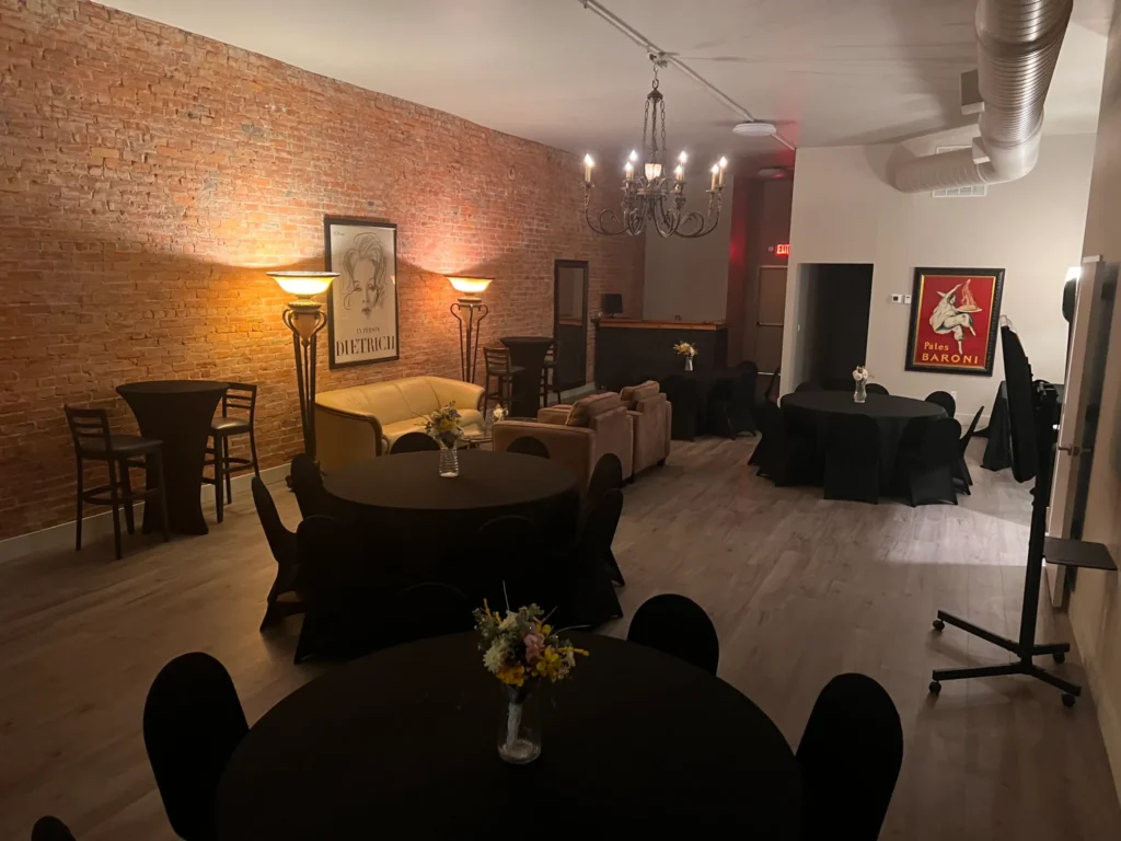 The room arranged for a standing reception, warm lamp light along the brick