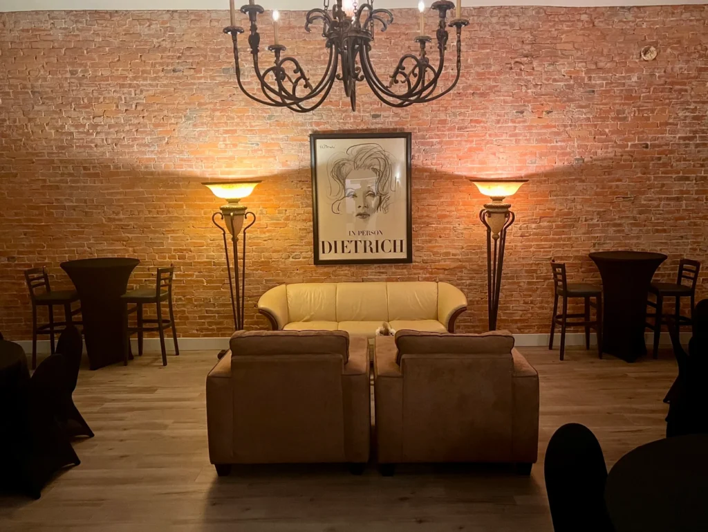 The lounge corner — leather seating under the chandelier beside the Dietrich print